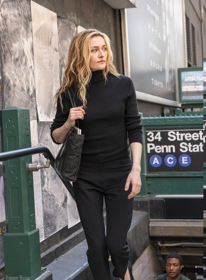 « Photographie de l’actrice Sarah Pidgeon incarnant Carolyn Bessette dans la série "Love Story" sur Disney+. Elle porte une silhouette minimaliste entièrement noire, emblématique du style Calvin Klein des années 90 réhabilité par la production en février